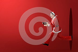 Asian man in Santa costume running while holding the gift box