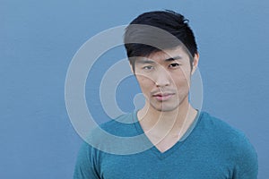 Asian man with serious expression over blue background with copy space