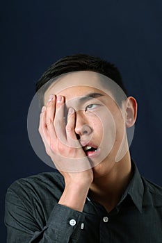 Asian man showing facepalm and rolling eyes up photo