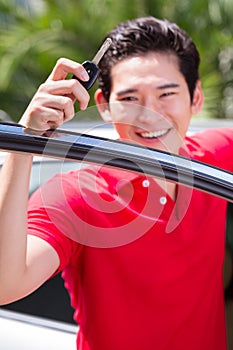 Asian man showing key of his car