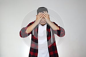 Asian man shows regret gesture, covering his face with hands and crying