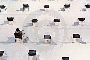 An Asian man sit and wait in rows of empty chairs with social distancing seatings during Covid-19 pandemic