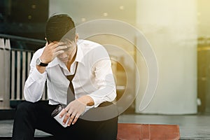 Asian man sits on the steps of an office building with stress an