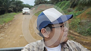 Asian man sitting in the back of pickup truck, outdoor safari trip adventure journey in the wild