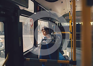 Asian man sitting dreaming on bus looking through window.