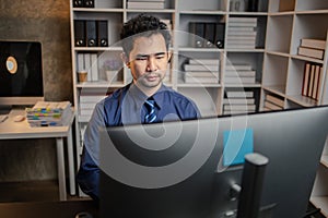 Asian man sitting in the office working overtime in the middle of the night, employee working overtime to get work done on time.