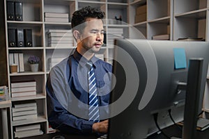 Asian man sitting in the office working overtime in the middle of the night, employee working overtime to get work done on time.