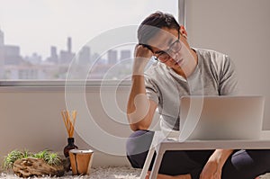 Asian man sitting in room and looking serious news at laptop