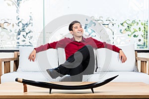 Asian man sitting on sofa in furniture store