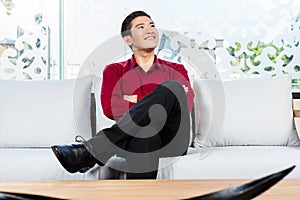 Asian man sitting on sofa in furniture store