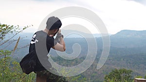 Asian man sitting at the wood chair and take a picture from top of mountain. Pang Sida National Park.