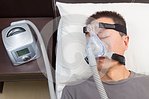 Asian man with sleep apnea using CPAP machine