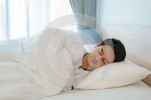 Asian man are sleeping and having good dreams in white blanket in the morning. Rest after work tiring in bedroom at home