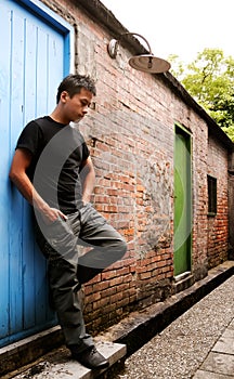 Asian man stand against a old door and lonely