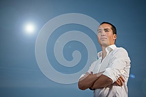 Asian man standing with arms folded