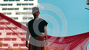 an Asian man standing in front of a building with a blue sky and red cloth flying