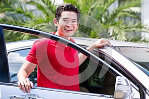 Asian man standing in front of car