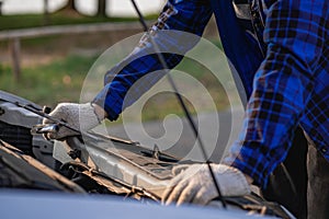 Asian man standing in front of inspection vehicle and inspecting machinery Problems in the car engine in the house and found probl