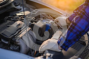 Asian man standing in front of inspection vehicle and inspecting machinery Problems in the car engine in the house and found probl