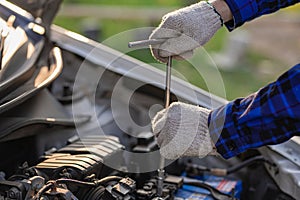 Asian man standing in front of inspection vehicle and inspecting machinery Problems in the car engine in the house and found probl