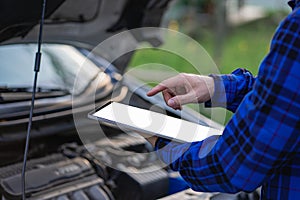 Asian man standing in front of inspection vehicle and inspecting machinery Problems in the car engine in the house and found probl