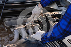 Asian man standing in front of inspection vehicle and inspecting machinery Problems in the car engine in the house and found probl