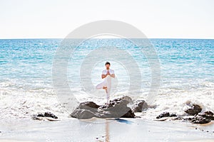 Asian man standing in yoga pose, on the beach