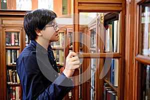 Asian man student choosing book in library