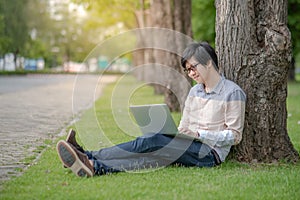 Asian man student using laptop in the park