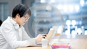 Asian man student using laptop and smartphone for study