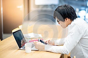 Asian man student using laptop and smartphone for study