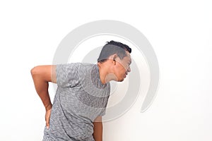 Asian man suffering from backache for having made an effort on isolated background