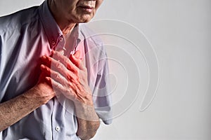 Asian man suffering from central chest pain. Chest pain can be caused by heart attack, myocardial infarct or ischemia, myocarditis photo
