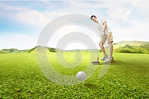 Asian man swing the golf club and hitting the ball