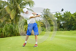 Asian man swinging club for tee-off in course