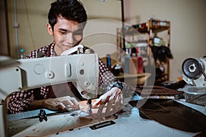 asian man tailor sewing leather using sewing machine