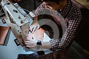 asian man tailor sewing leather using sewing machine