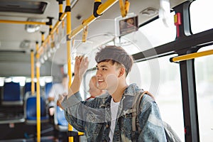 Asian man taking public transport, standing inside bus.