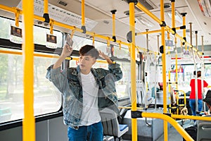 Asian man taking public transport, standing inside bus.