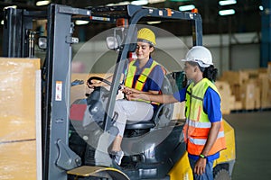 Asian man teaching woman driver drive fork lift car in industry with smile, ability of girl and diversity of career wearing helmet