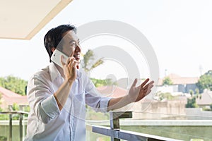 Asian man telephoning on balcony with mobile phone