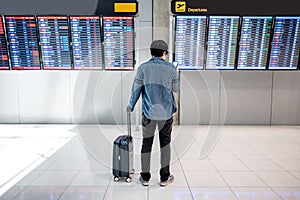 Asian man tourist at arrival departure board in airport