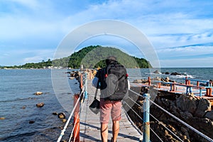 Asian man tourist backpaker walking on wooden bridge with rope rail bridge to viewpoint to see white pagoda on the stone in the
