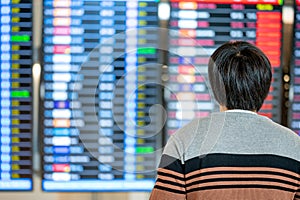 Asian man tourist looking at arrival departure board