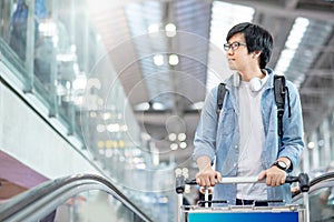 Asian man tourist walking with trolley in airport