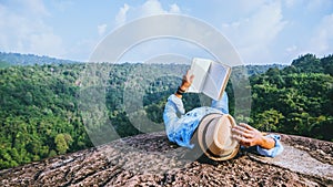 Asian man travel relax in the holiday. sleep relax read books on rocky cliffs. On the moutain summer photo