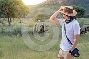 Asian man traveler standing in safari looking at wildlife animals