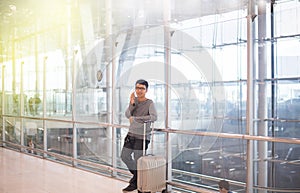 Asian man traveler using mobile phone in airport,Lifestyle using cell phone connection concept,Feeling happy and smiling