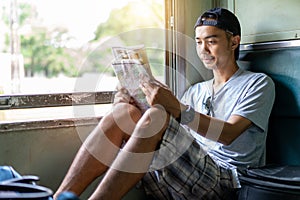 Asian man traveling backpacker reading map sit on the old train seat