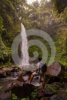 Asian man traveller enjoying waterfall landscape in tropical forest. Man with backpack. Energy of water. Travel lifestyle. View